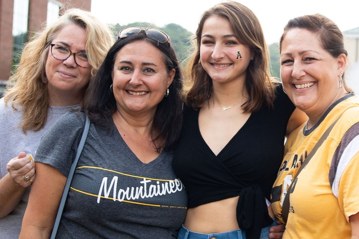 Student and her mom pose with friends during Family Weekend